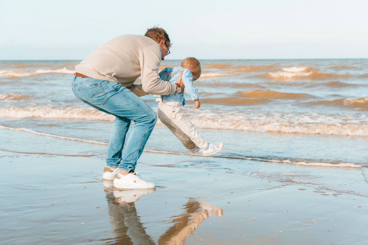 A playful scene of chasing and running along a sandy beach at sunset.