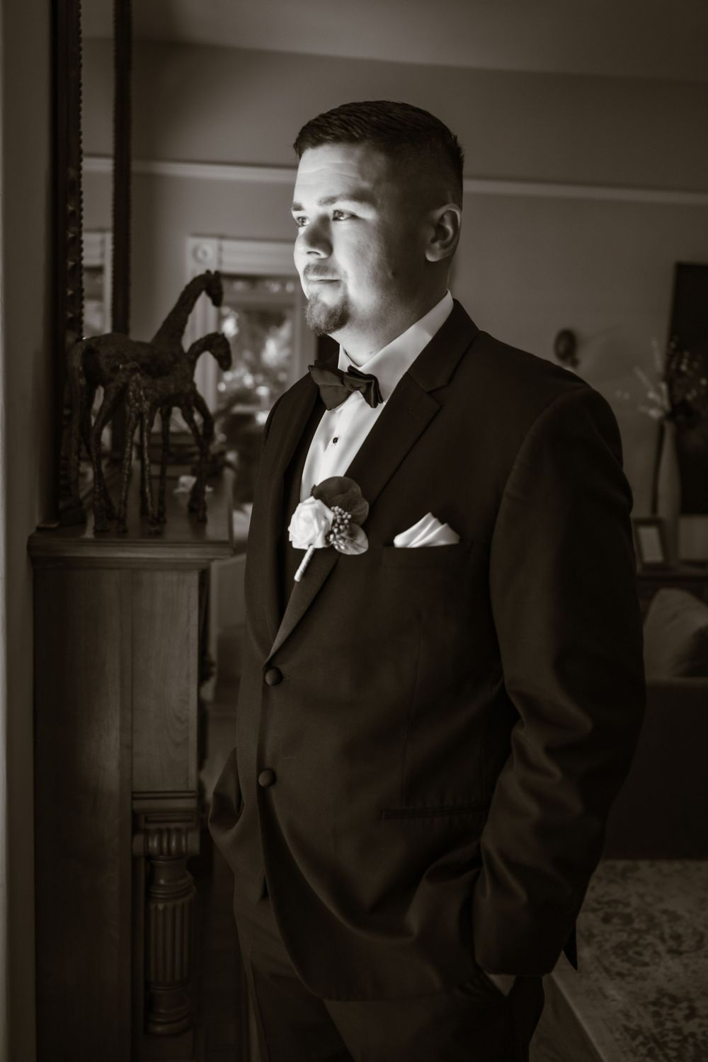 Artistic black and white portrait of groomsman in formal attire.