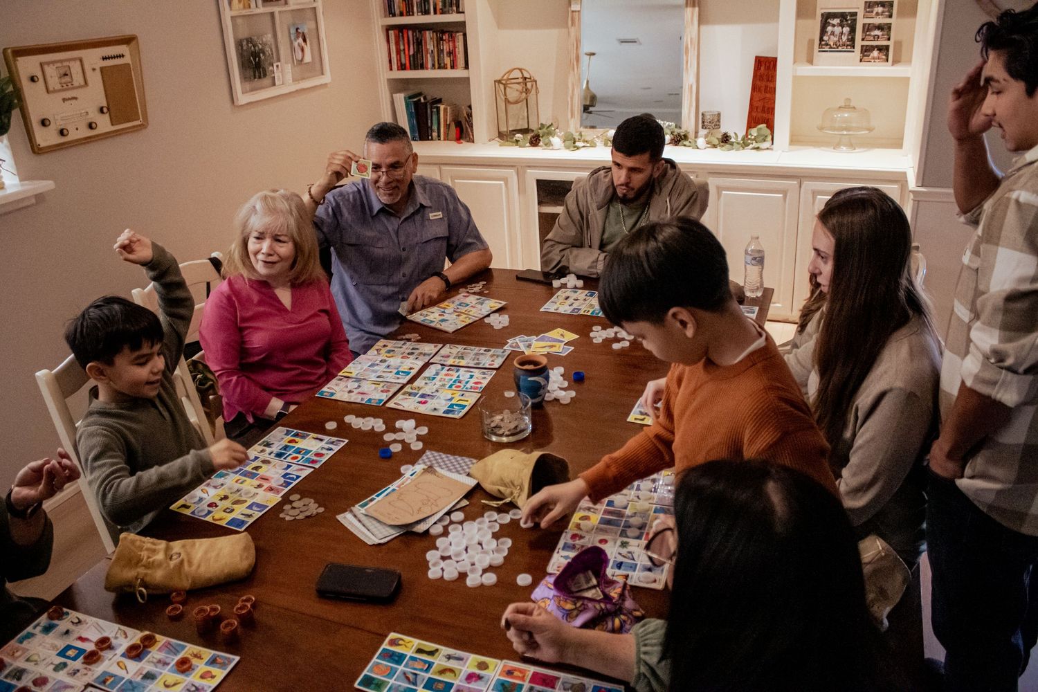 A group gathered around a wooden table playing a card game together in a cozy home setting.