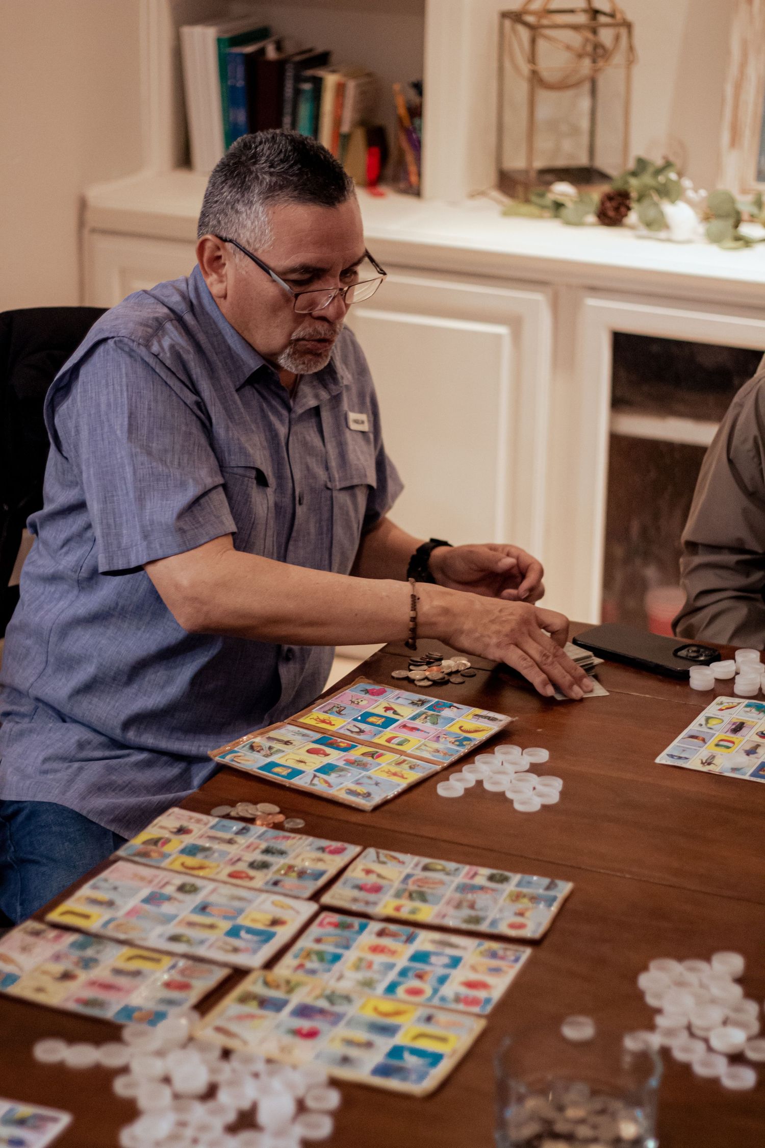 Players gathered around a wooden table with bingo cards and chips during an indoor game night.