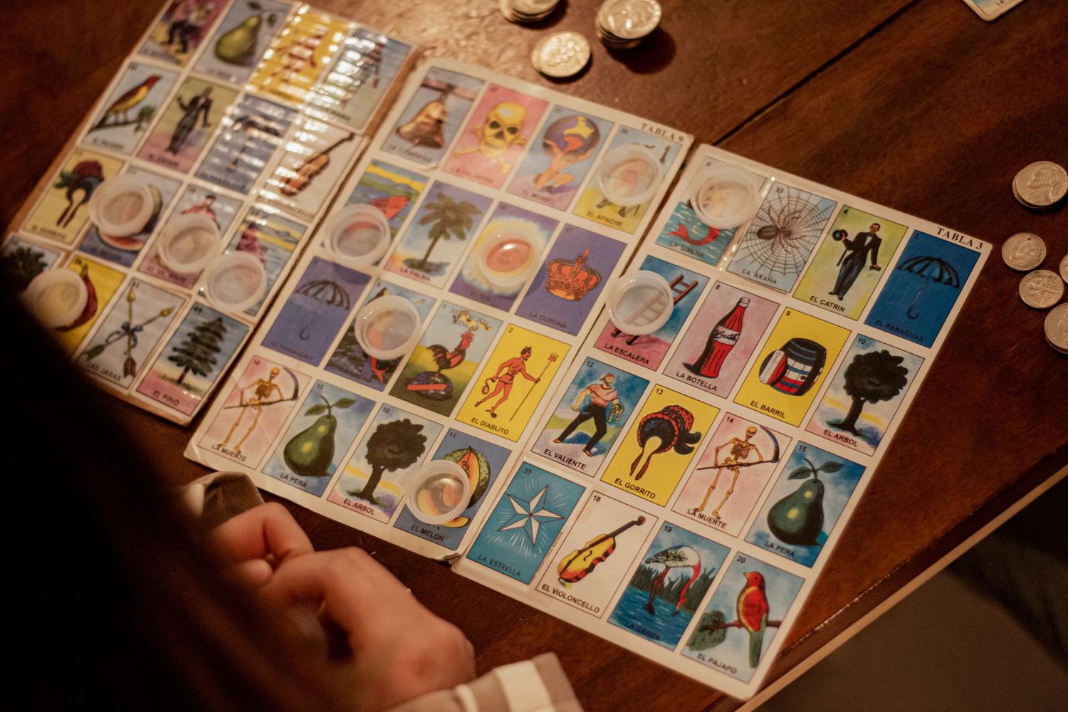 Colorful Mexican loteria cards laid out on a wooden table during a game.