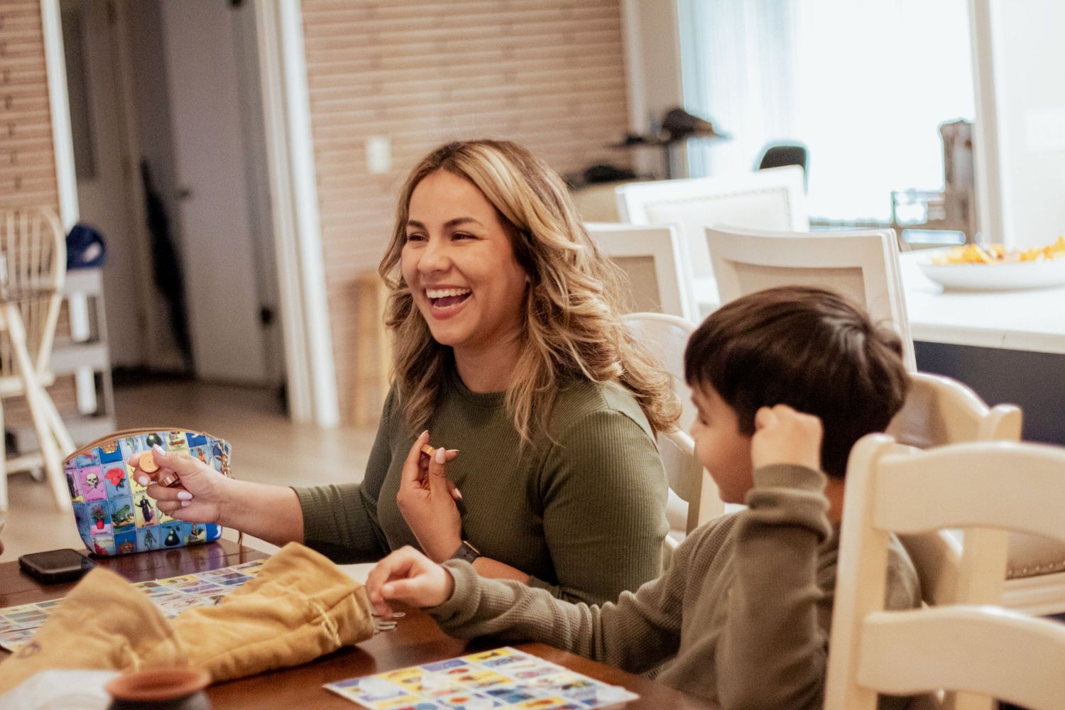 Parent and child sharing quality time together while playing board games at the dining table.