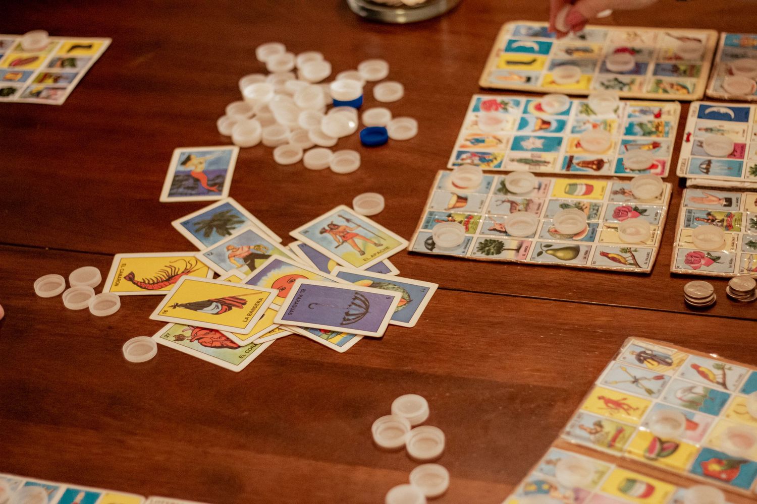 Board game pieces including cards, tokens, and game boards scattered on a wooden table during gameplay.