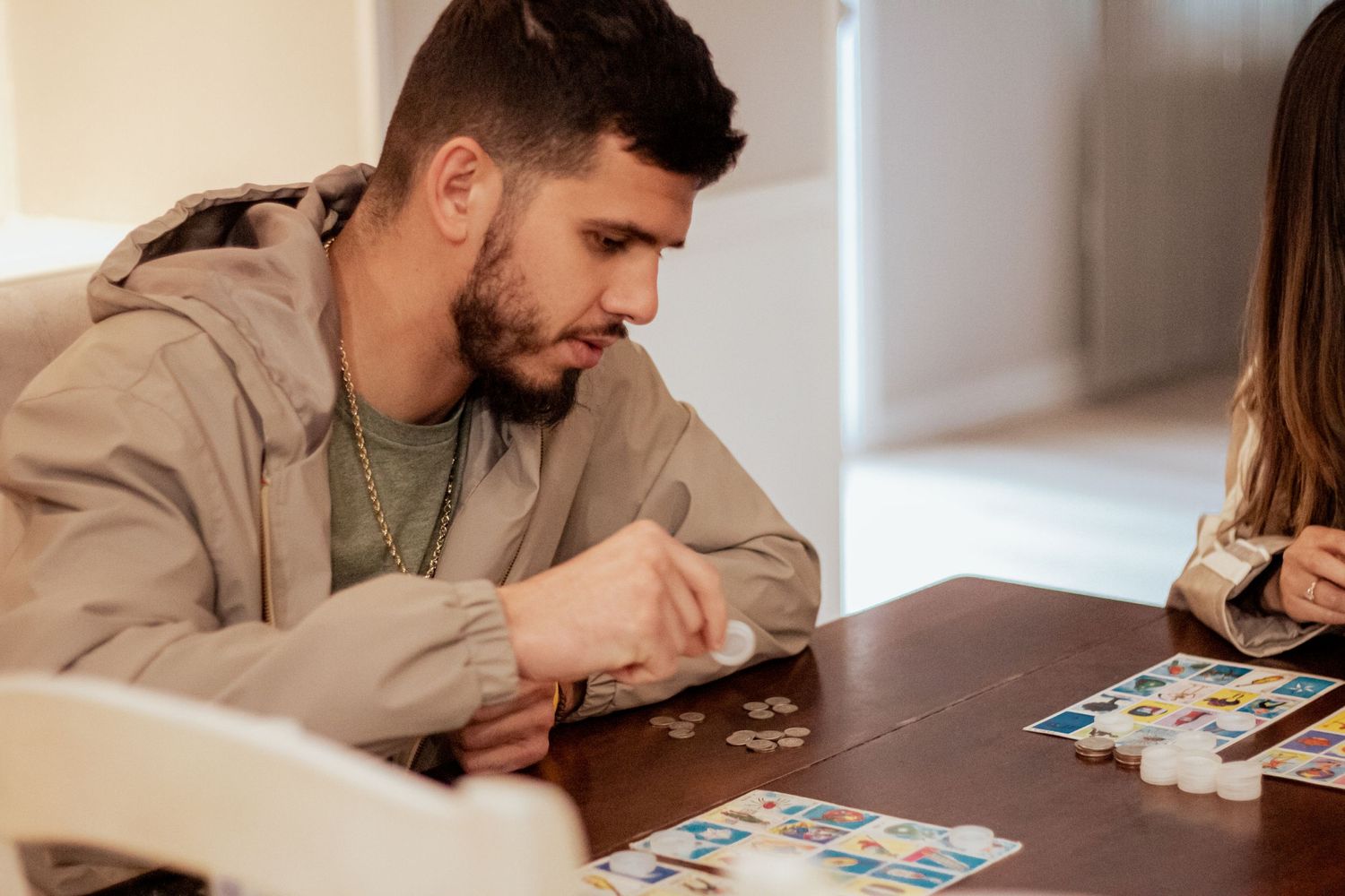 Two people sit at a table playing a board game together while concentrating on their next moves.