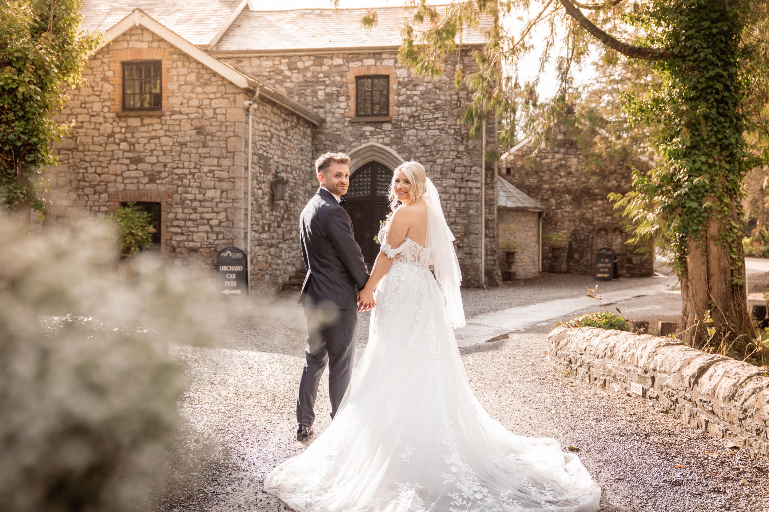 Romantic wedding portrait in front of stone building with ivy and natural lighting.