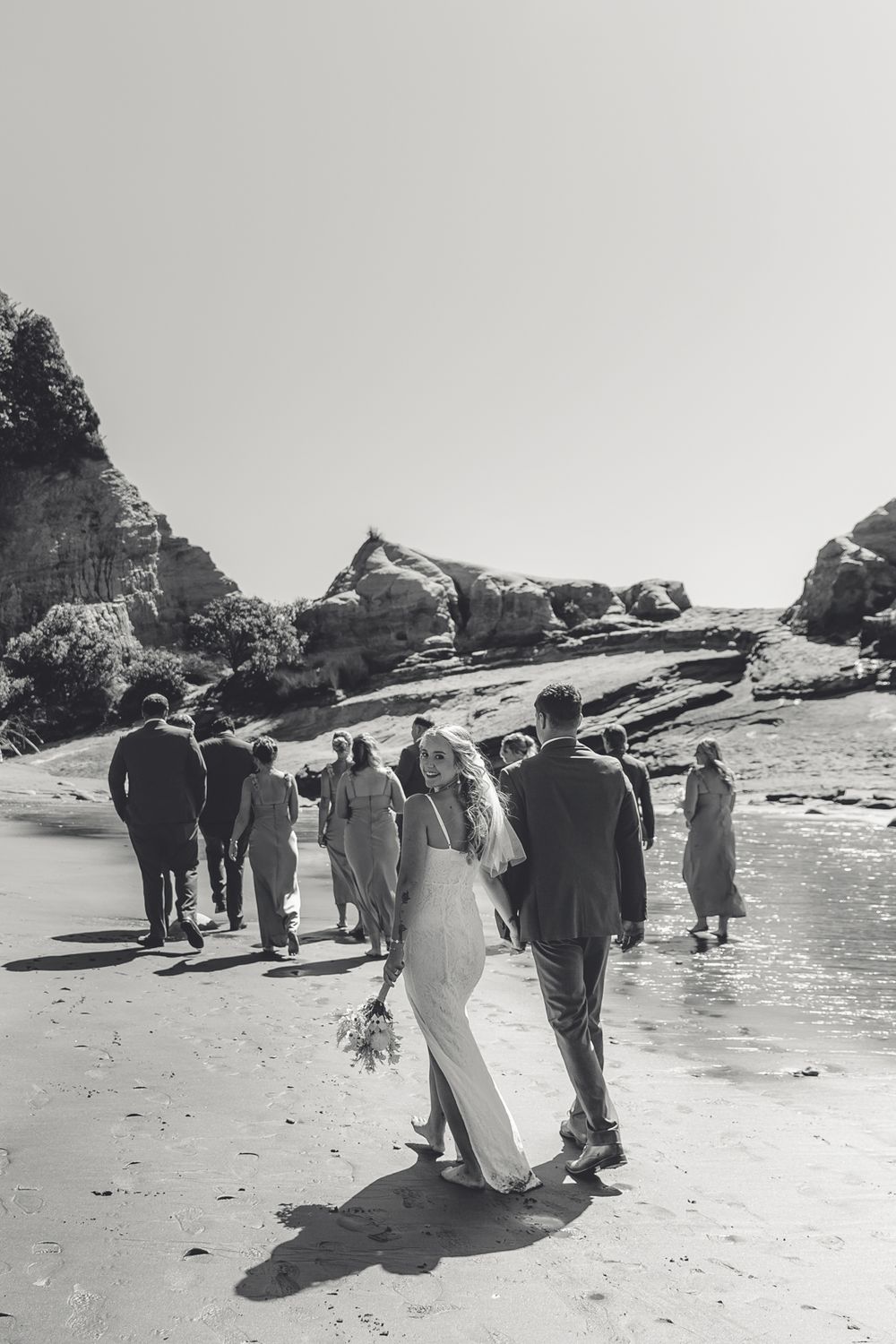 Bride and groom holding hands on a windswept West Coast NZ beach