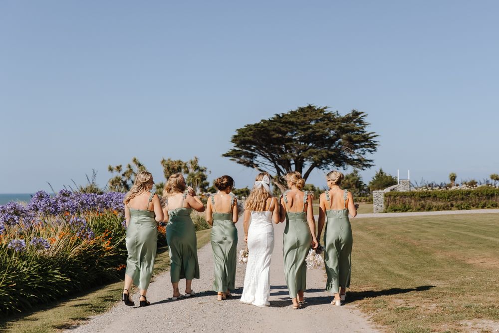 Wedding party walking together along the coastline in New Zealand during sunset