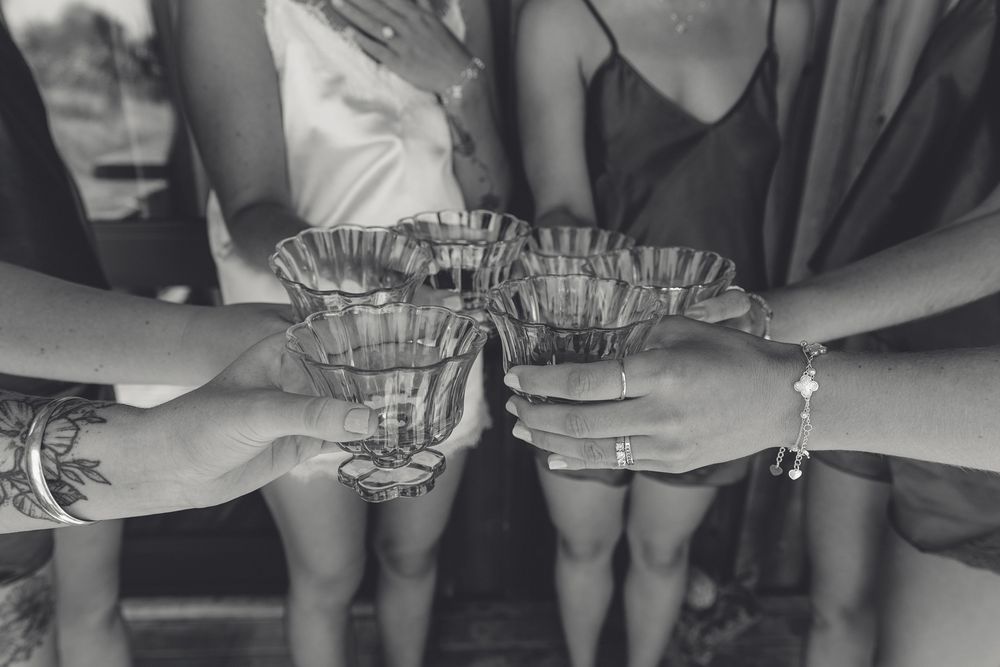 bride and her bridesmaids cheers to getting ready with a black and white details moment captured ahead of their west coast beach wedding