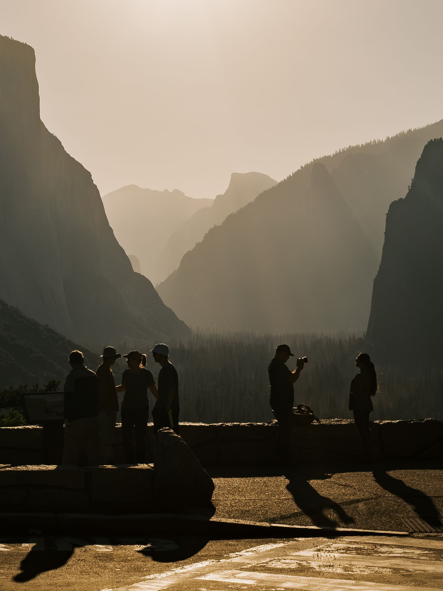 Silhouettes of people admiring the scenic mountain valley vista at Yosemite National Park during sunset.