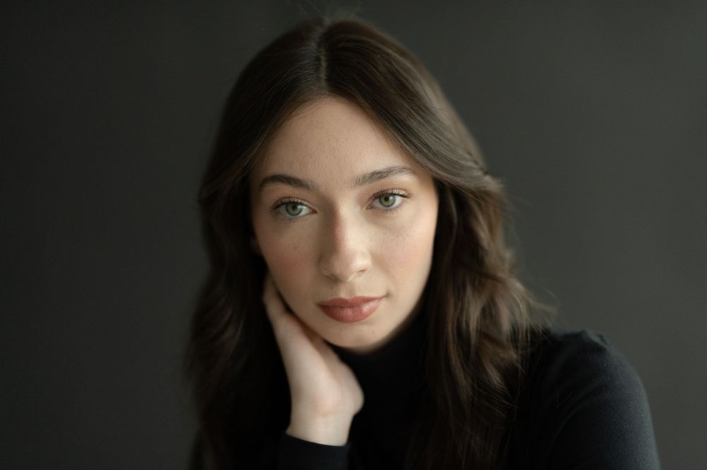 Close-up portrait of a person in black sweater with soft, natural pose.