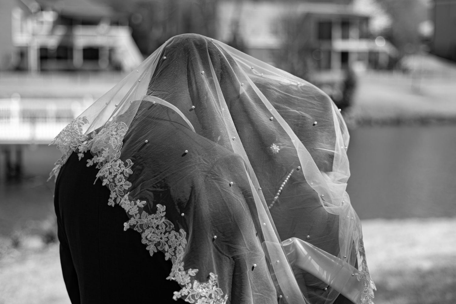A delicate lace wedding veil captured in black and white with intricate embroidery details.