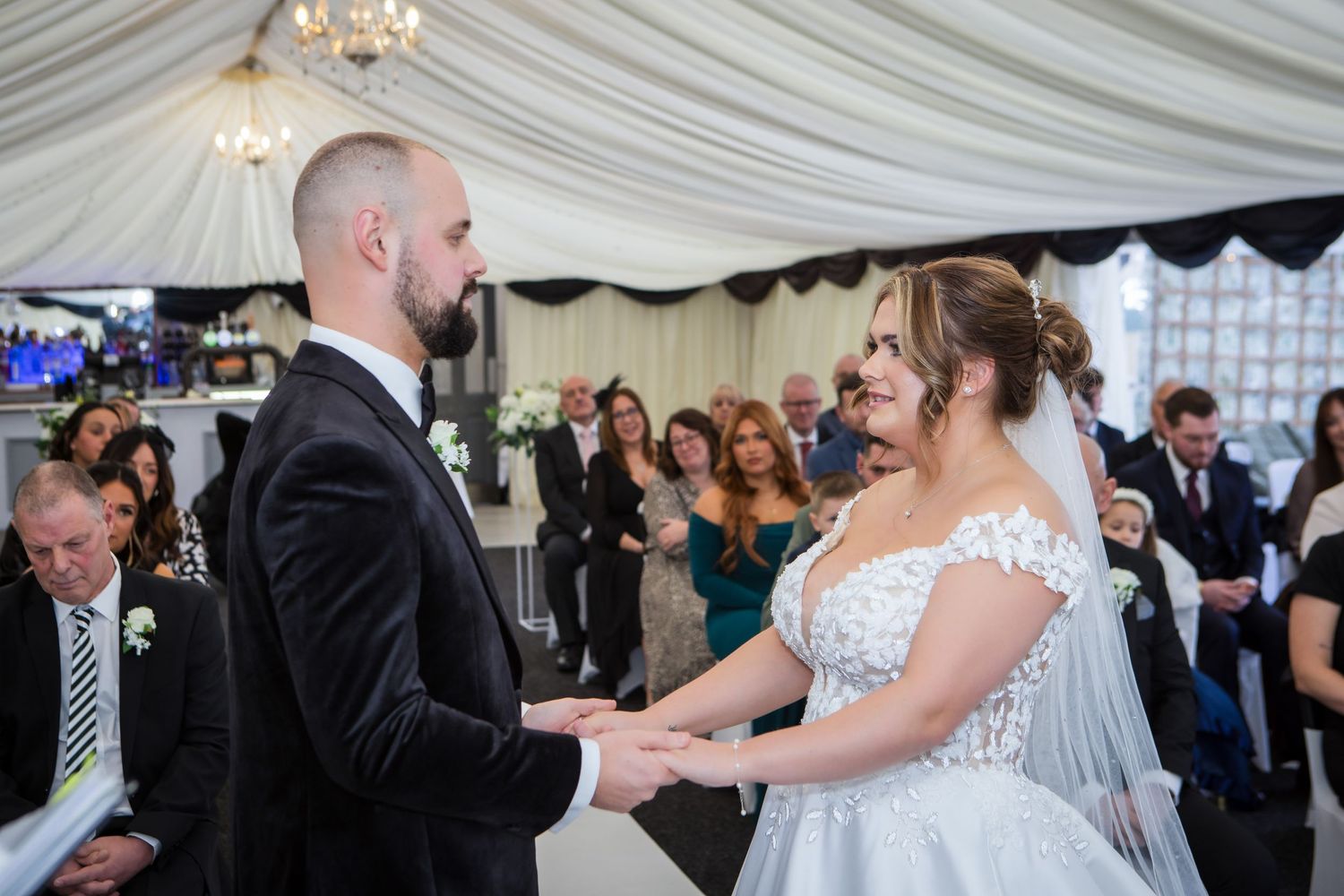 Couple exchanging vows during wedding ceremony in a beautifully decorated tent venue.