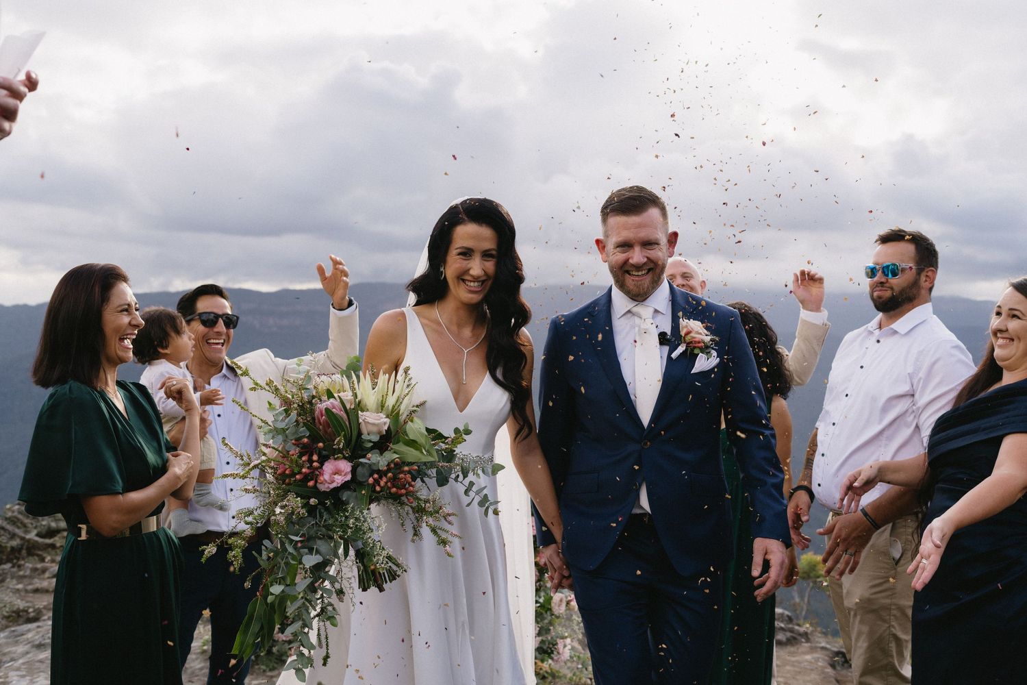 Wedding celebration on mountain overlook with confetti and scenic backdrop.