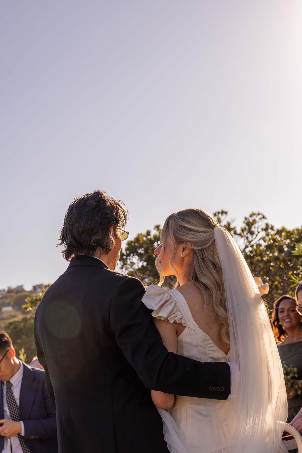 Bride and groom share a romantic moment at outdoor wedding ceremony, bride wearing white gown and veil.