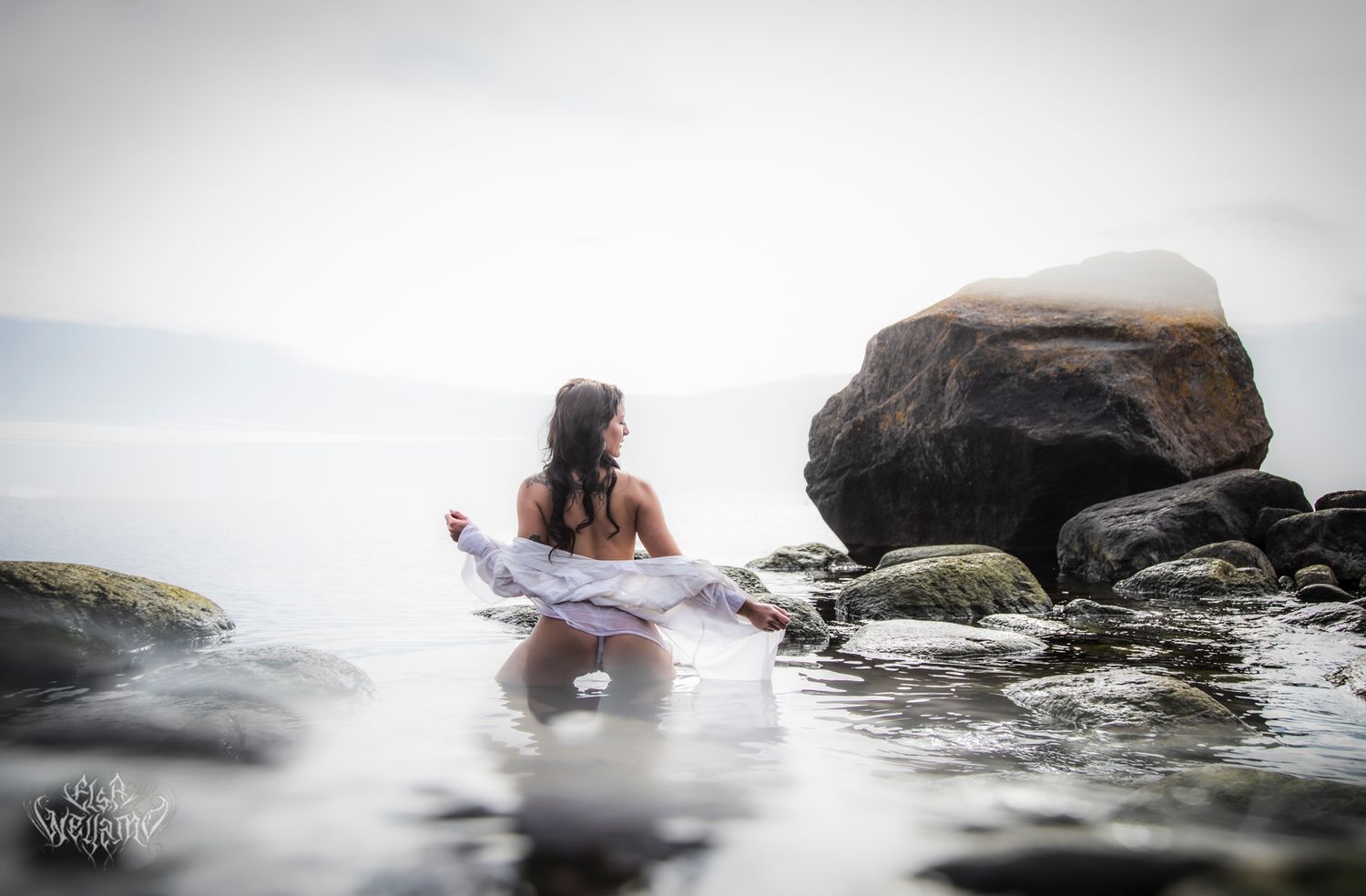 A person floats serenely in foggy waters surrounded by large rocks during a peaceful kayaking session.