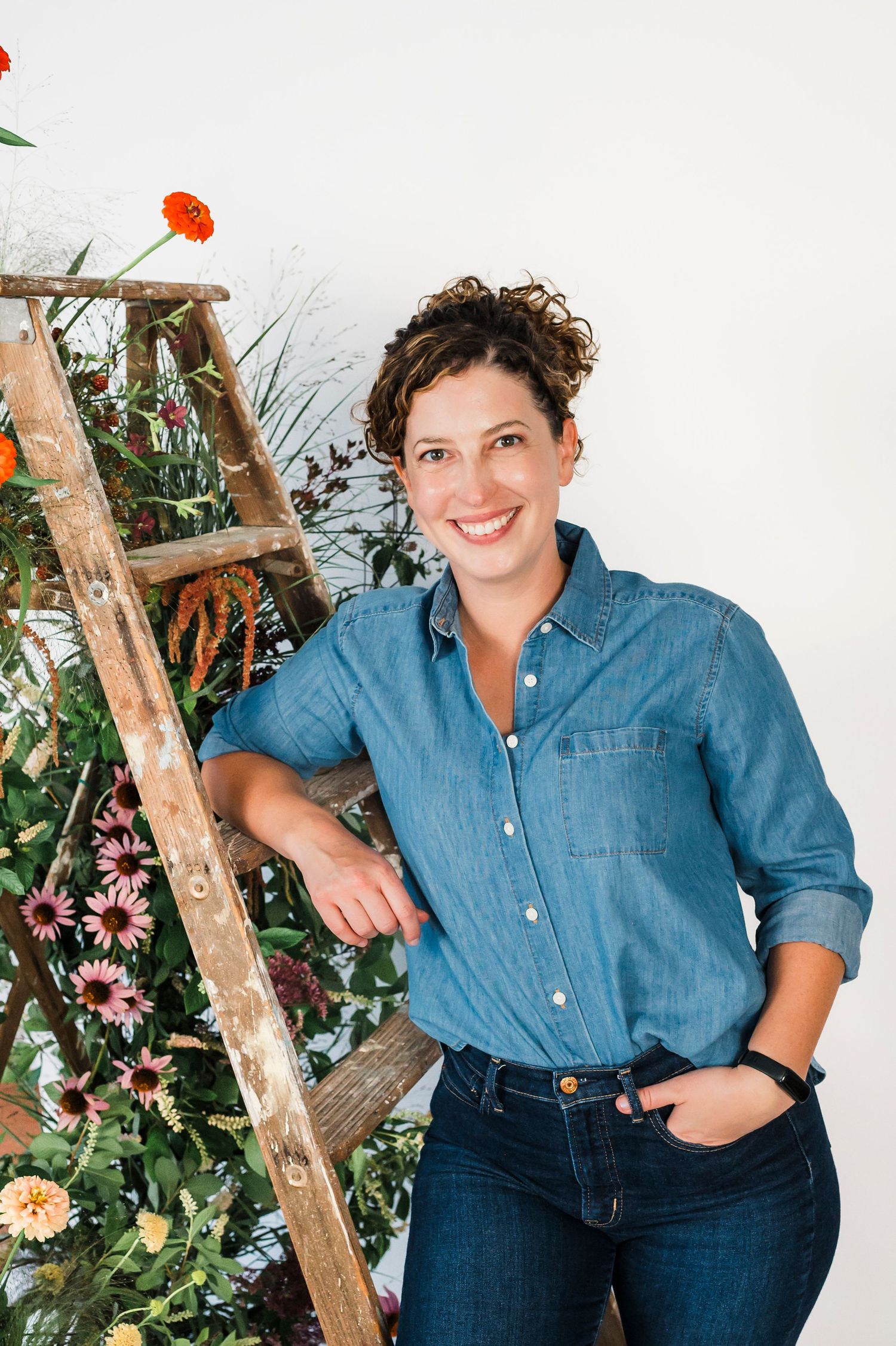 Studio portrait against white background featuring floral off-shoulder top and casual style.