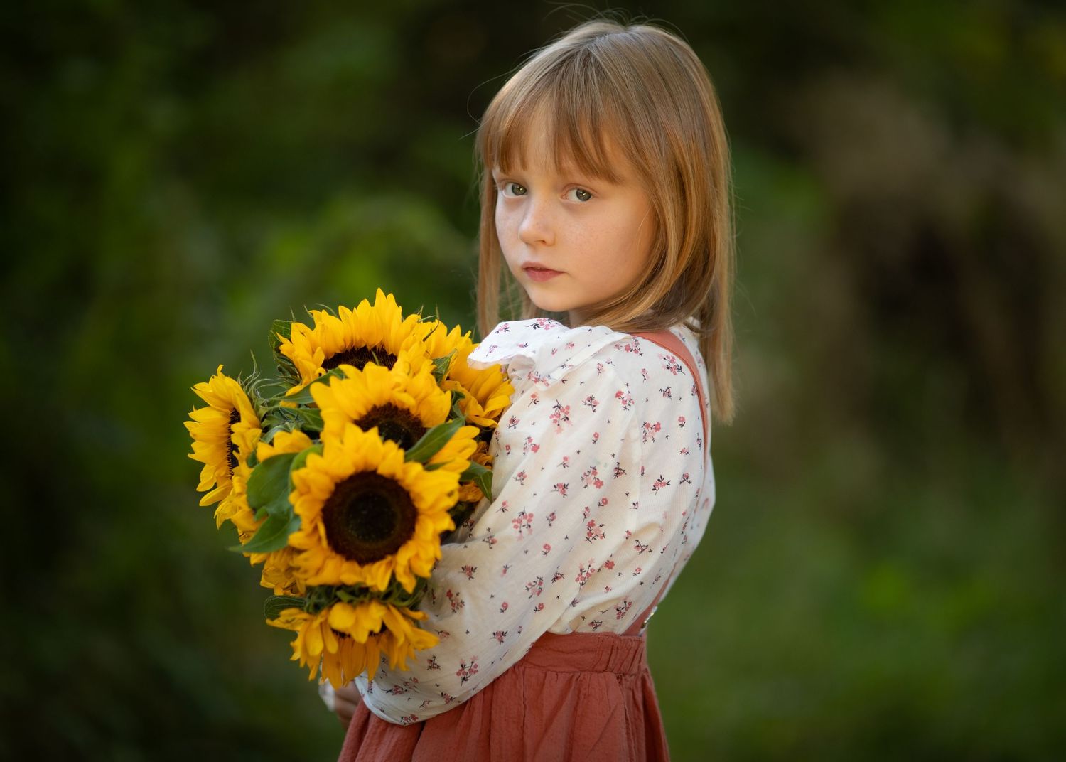 A beautiful bouquet of bright yellow sunflowers held against a natural outdoor background.