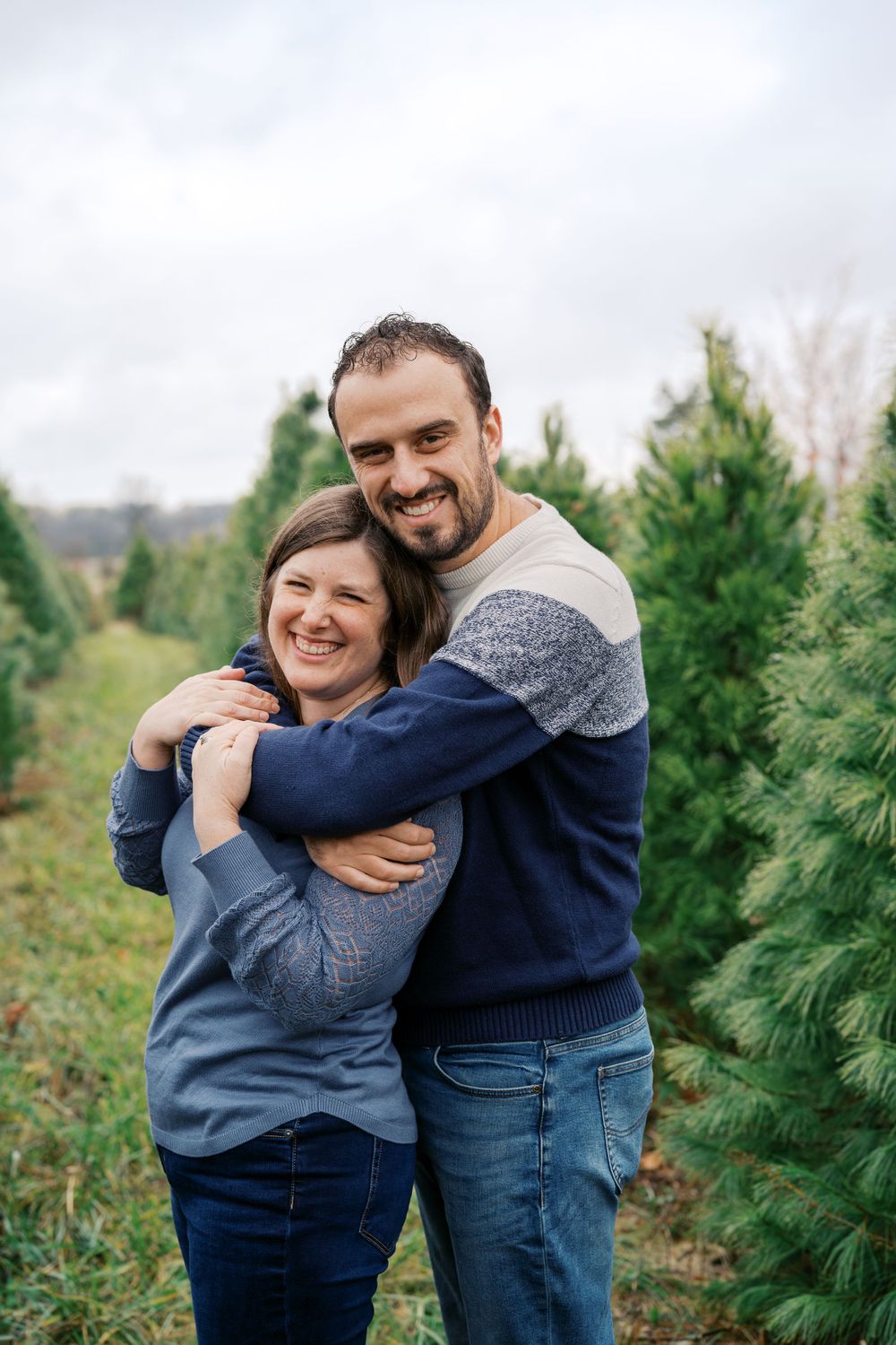 Candid embraces shared between people at a Christmas tree farm.