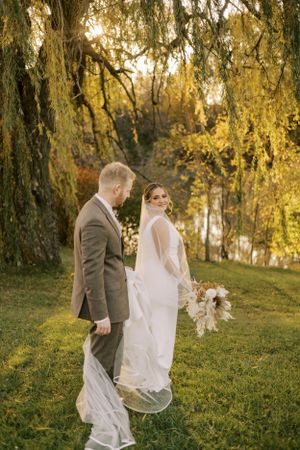 Newlyweds pose under a weeping willow tree during golden hour.