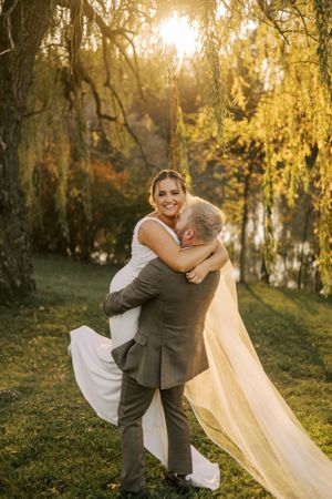 A joyful wedding moment captured as a couple embraces in golden evening light.