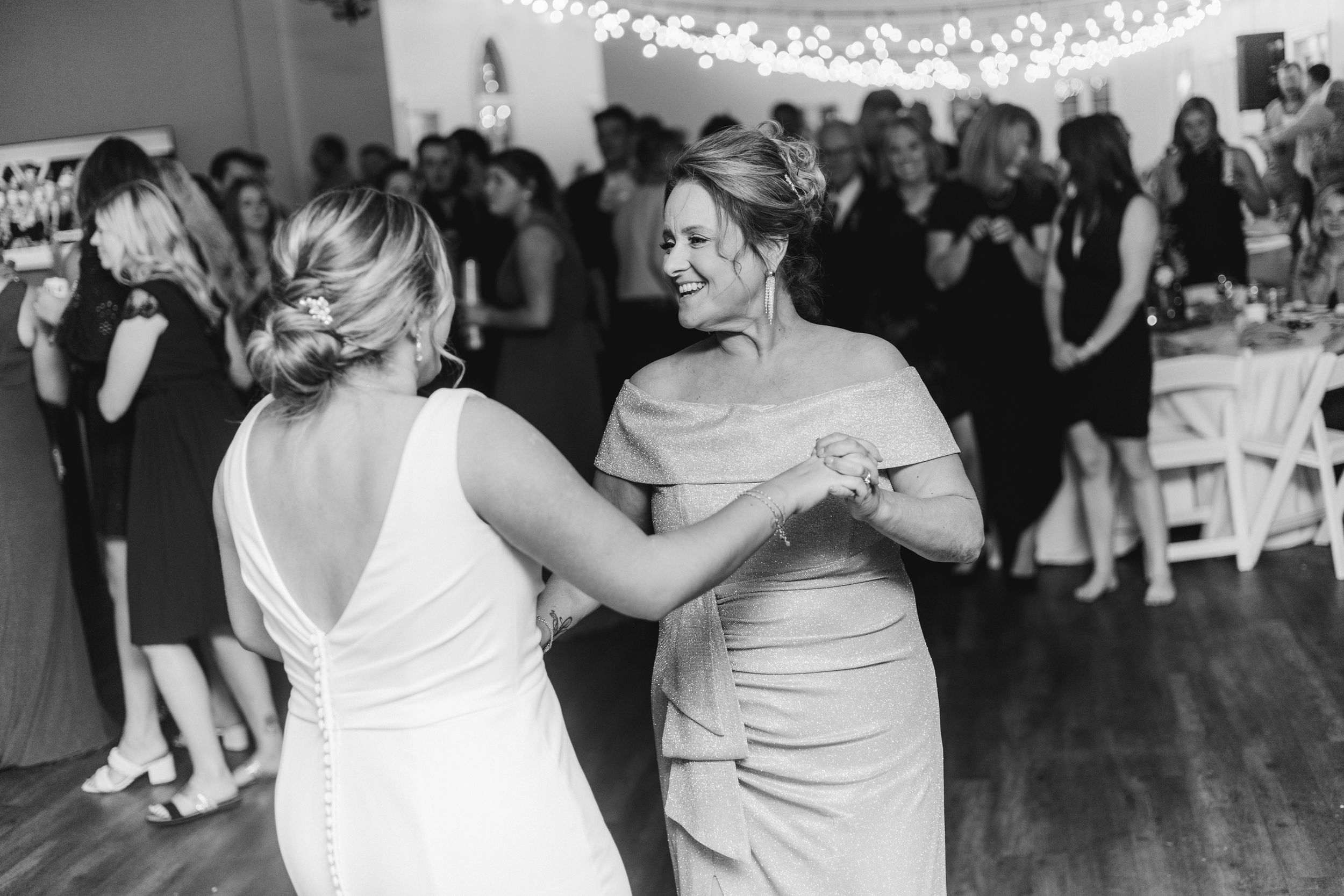 Black and white photo of two people dancing together at wedding reception.