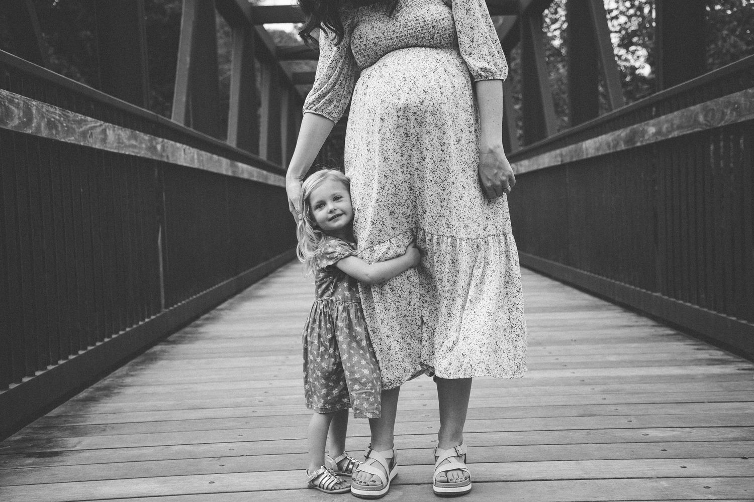 Black and white image of figures walking on a wooden boardwalk.