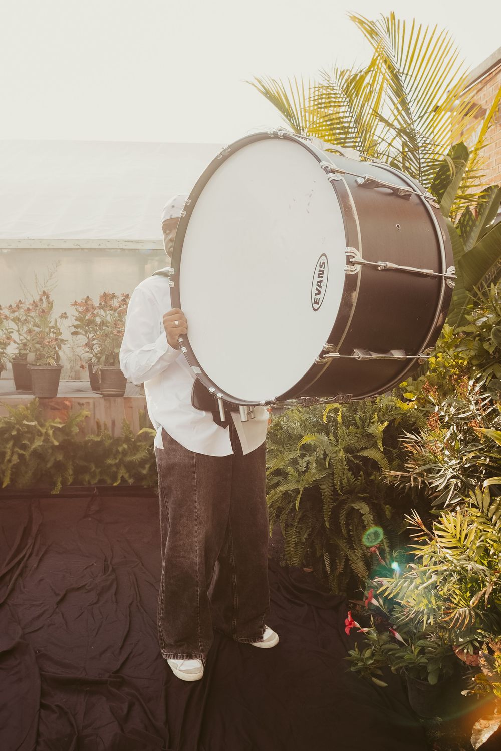 A white djembe drum is shown in five progressive angles against a dark background with tropical plants.