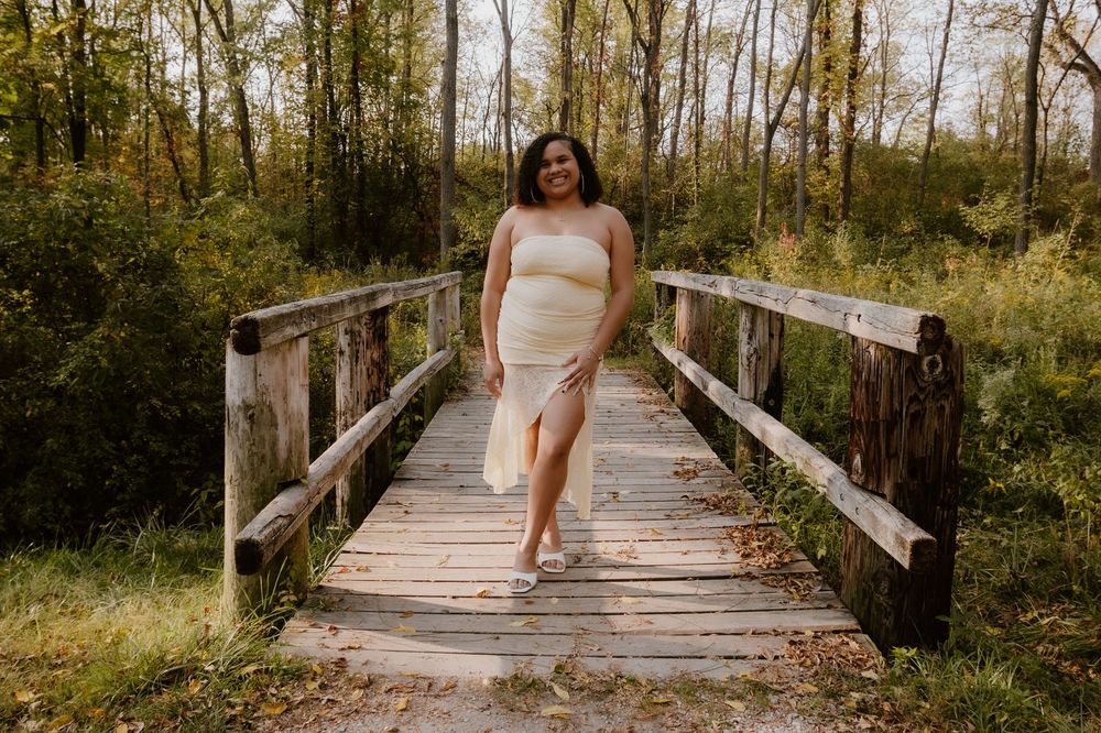 A wooden bridge path through a sunlit forest creates a romantic outdoor setting for wedding photography.