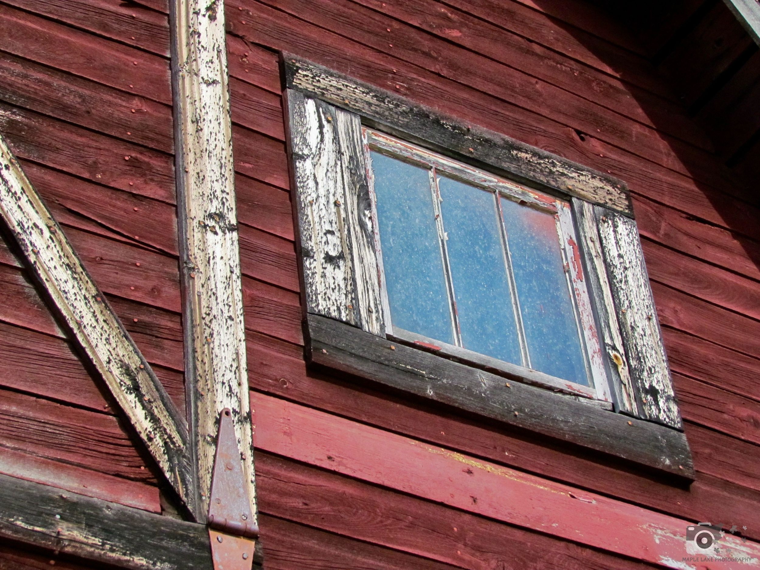 Weathered red barn with peeling paint and old window frame.