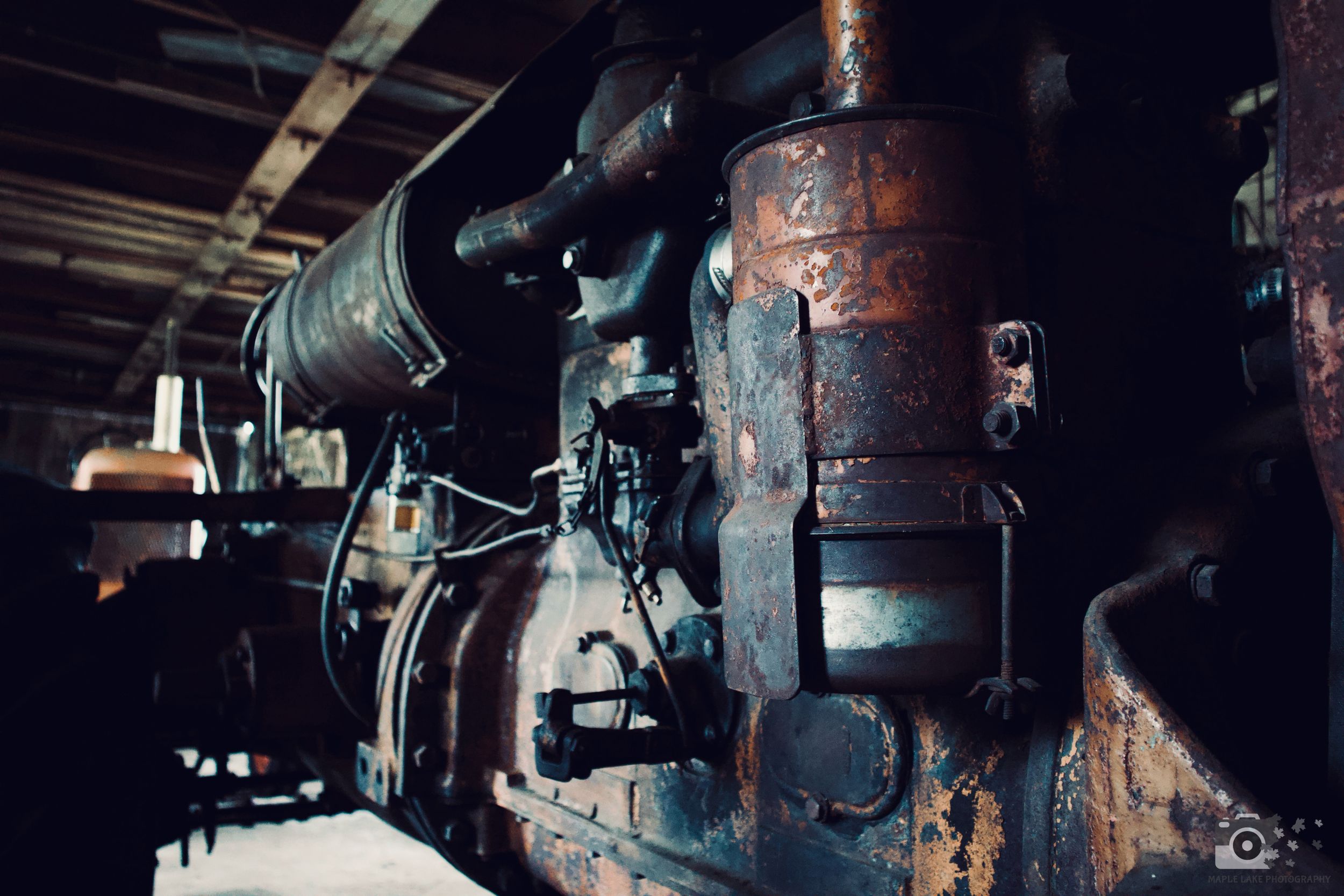 Rusty vintage industrial machinery with pipes and valves in dark lighting.