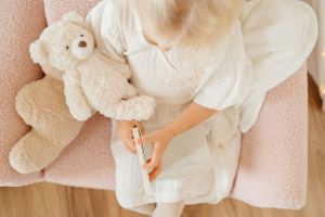 White teddy bear resting on a pink armchair with soft textiles.