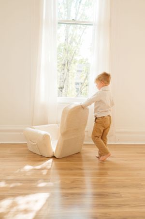 Light-filled room with cream colored chair and sunlight streaming through tall window.