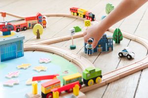 Closeup of wooden toy train track with colorful buildings and accessories.