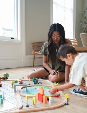 Interactive playtime with wooden train set featuring bridges and buildings on hardwood floor.