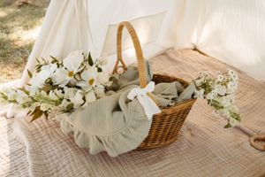 Rustic wicker picnic basket with white linen and floral arrangements.