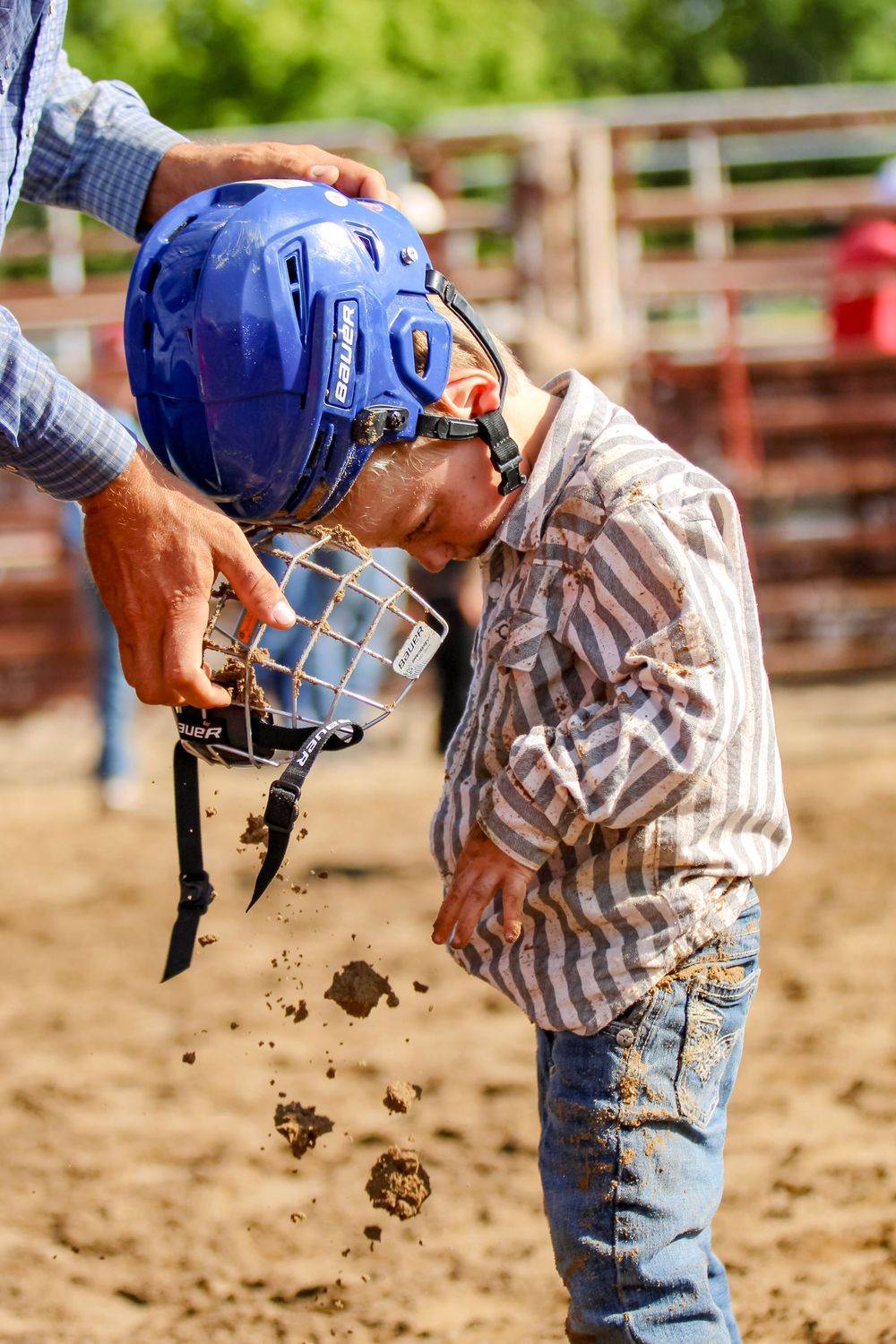 Mutton buster empties dust from his helmet.