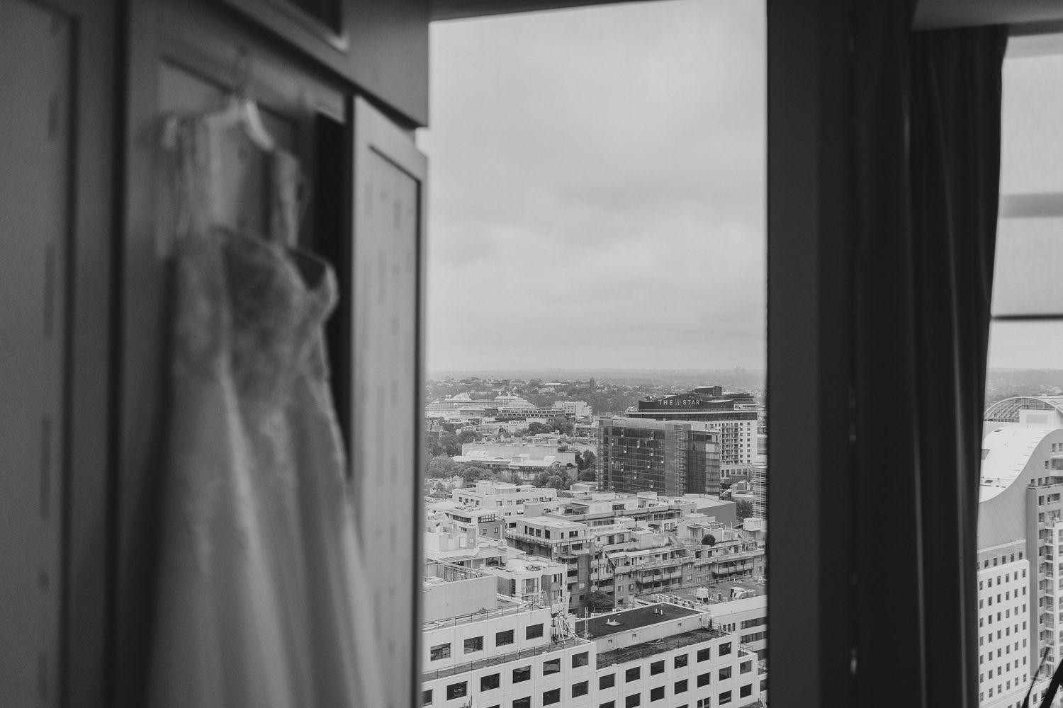 View of a cityscape through a window with a wedding dress visible in the foreground.