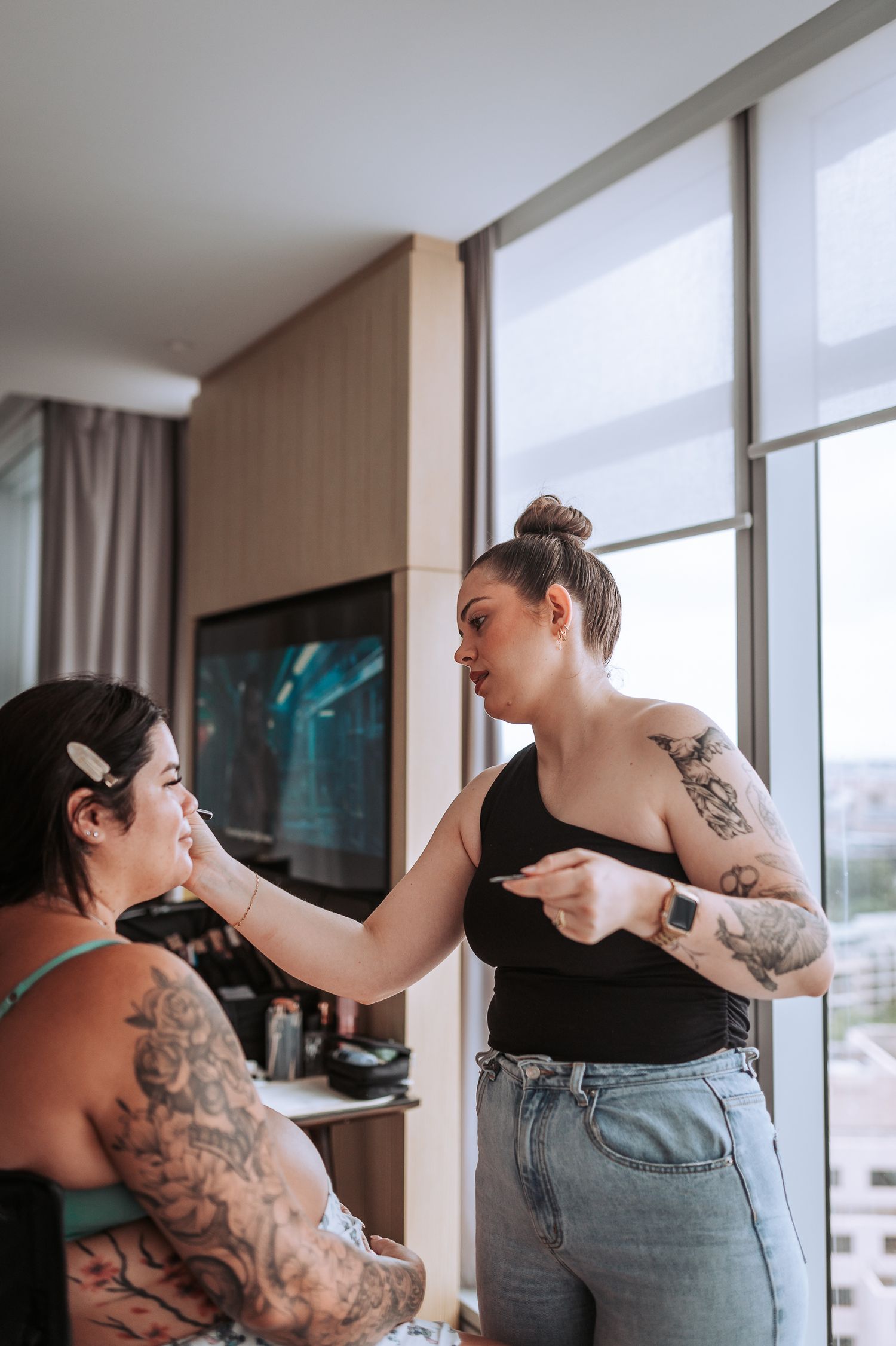 Wedding preparation scene with makeup being applied in a modern high-rise room.