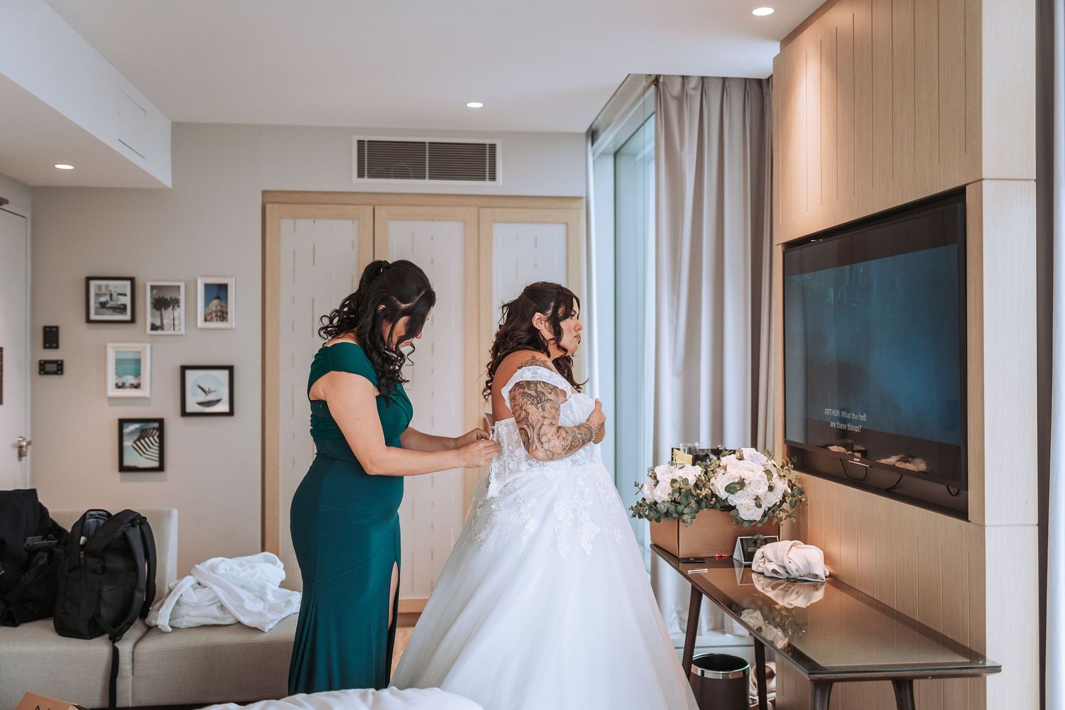 A wedding dress fitting in a bright modern room with large windows.