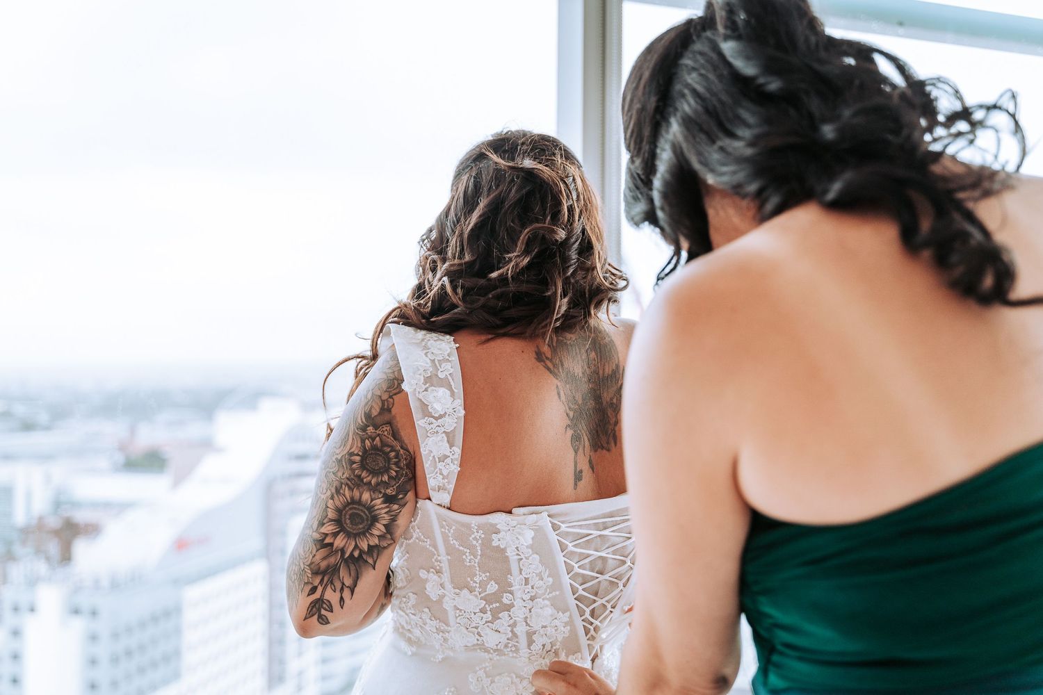 Wedding preparation scene overlooking city skyline through large windows.