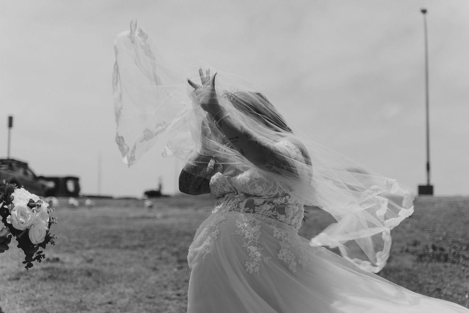 Black and white image of bride's veil flowing dramatically in the wind.