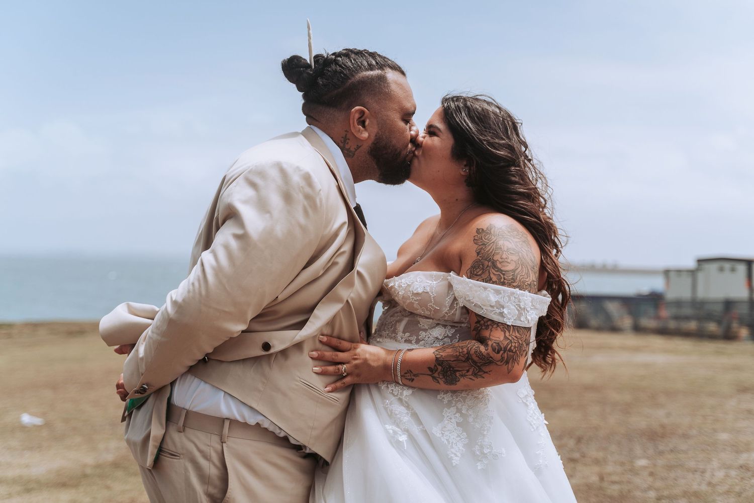 Romantic kiss between newlyweds during seaside wedding ceremony.