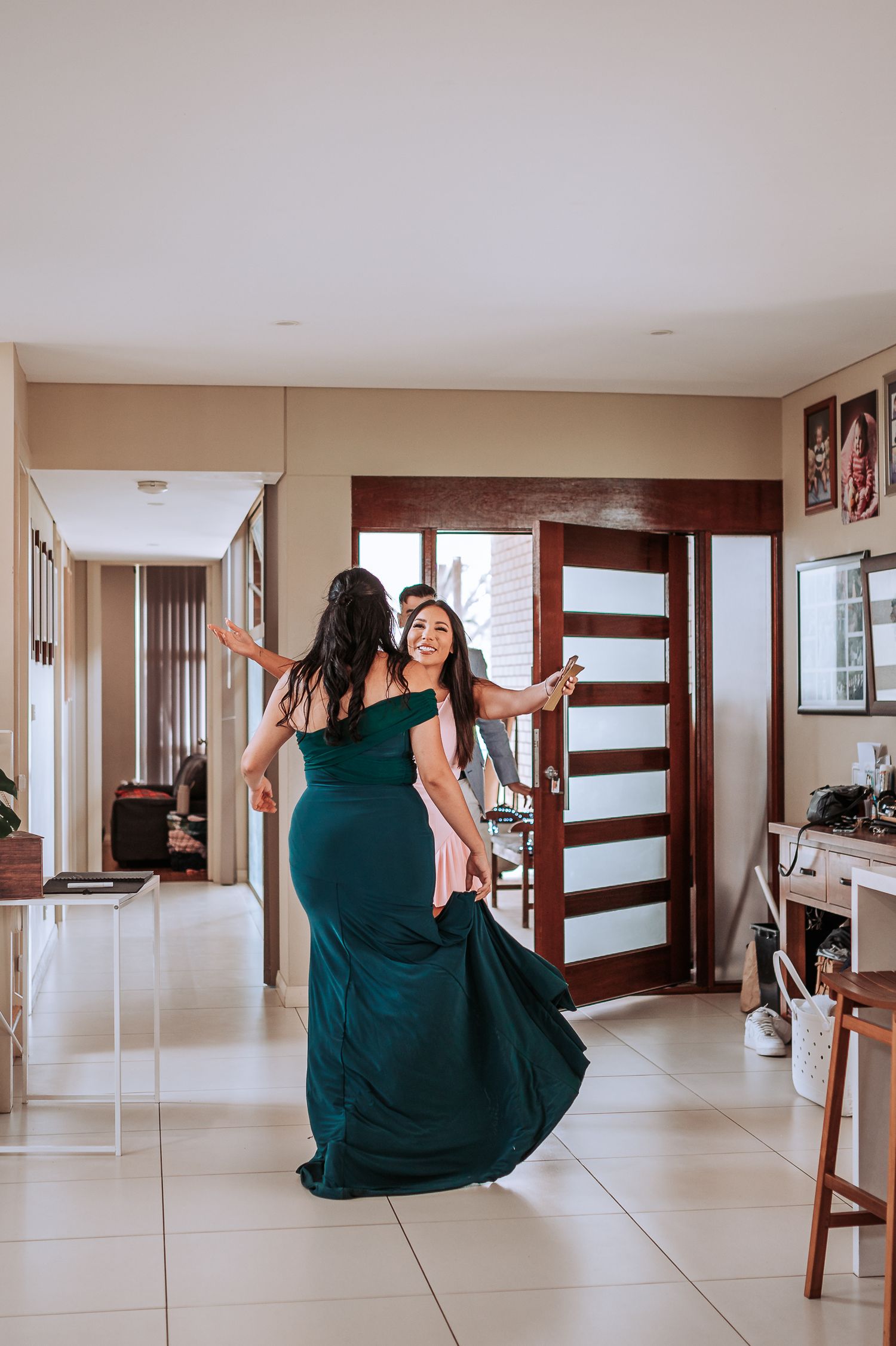 Person in emerald green formal dress twirling in a modern hallway.