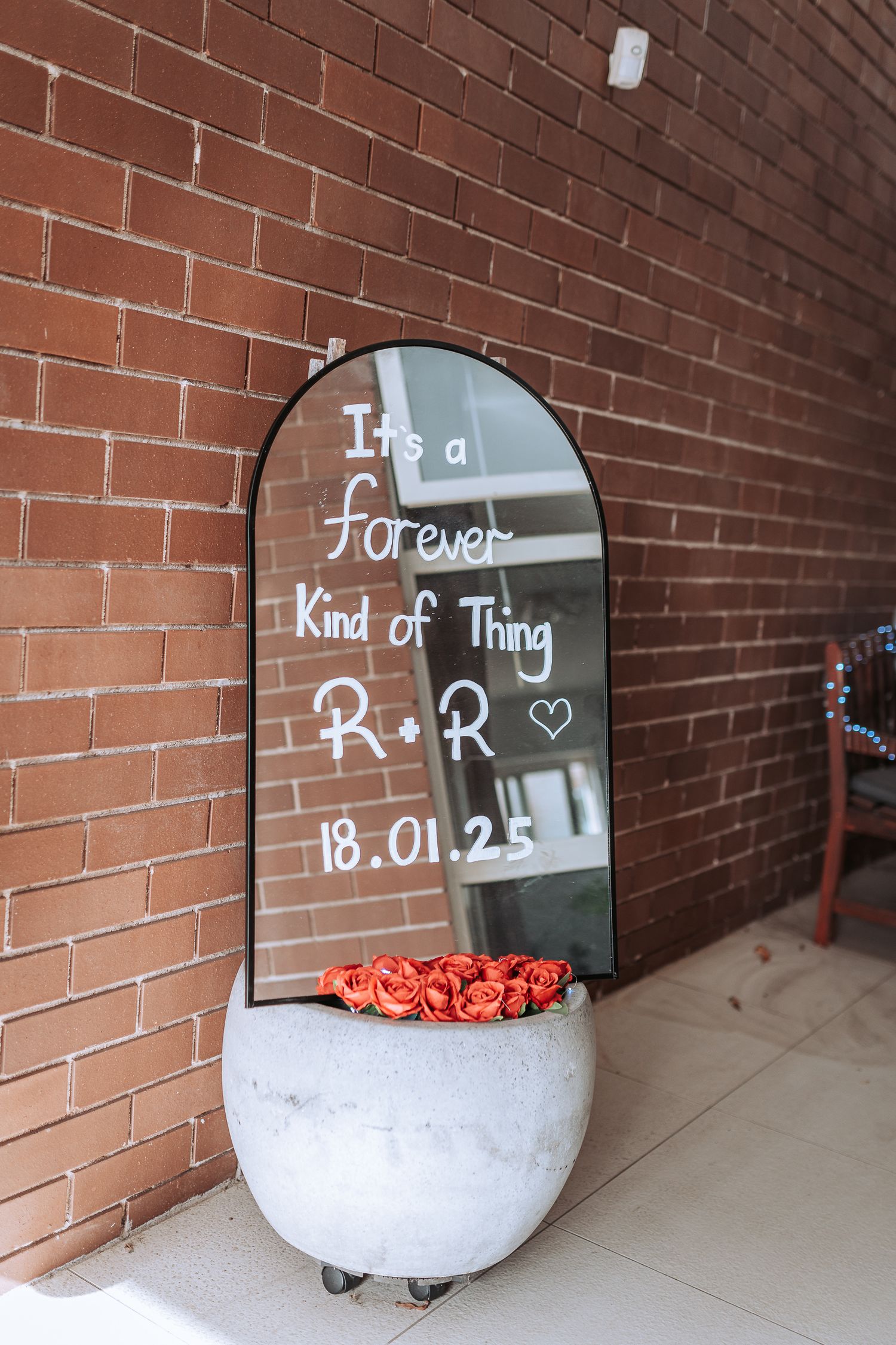 Mirror sign reading 'It's a forever kind of thing' with date displayed against brick wall.