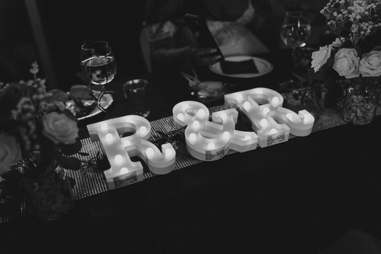Black and white photograph of illuminated marquee letters on dark table.