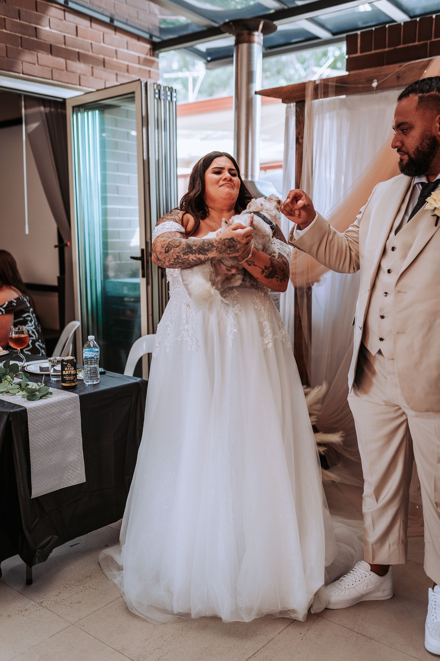 Couple dancing at indoor wedding reception with white decor and brick walls.