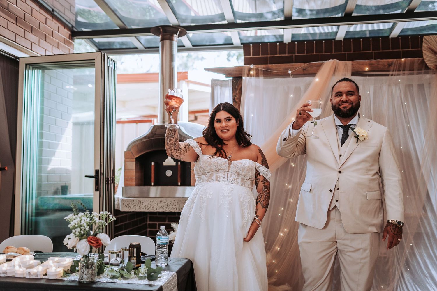 A jubilant newlywed couple celebrates during their reception in a modern venue with brick walls and skylights.