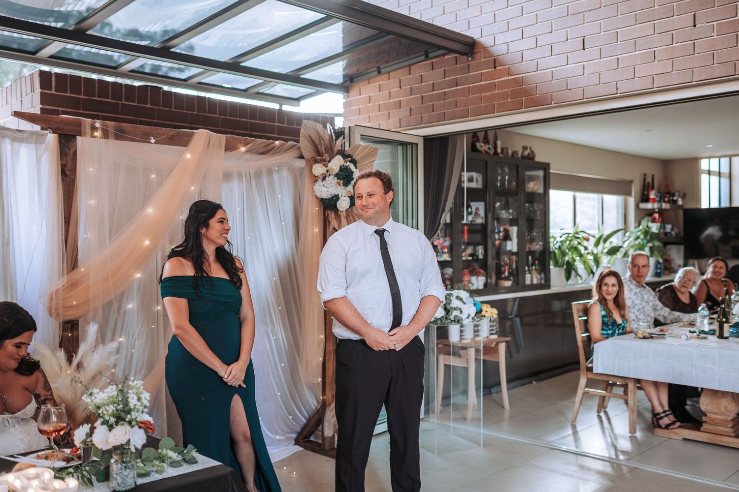 Wedding guests mingle in an modern indoor venue with exposed brick walls and natural lighting.