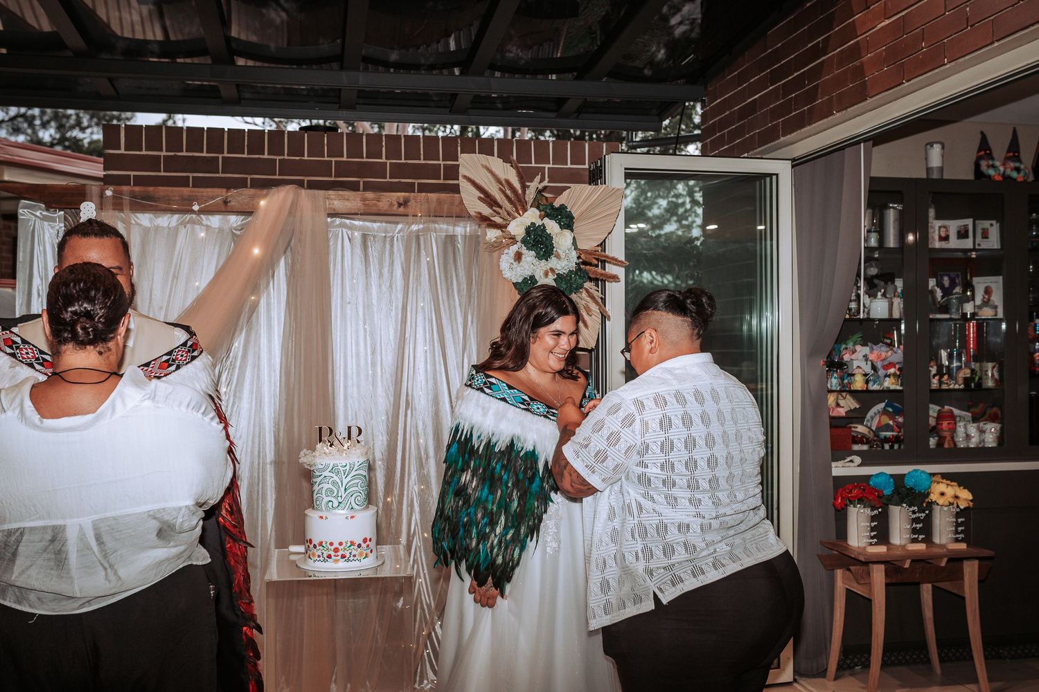 Wedding party celebrates with energetic dancing during reception in brick-walled venue.