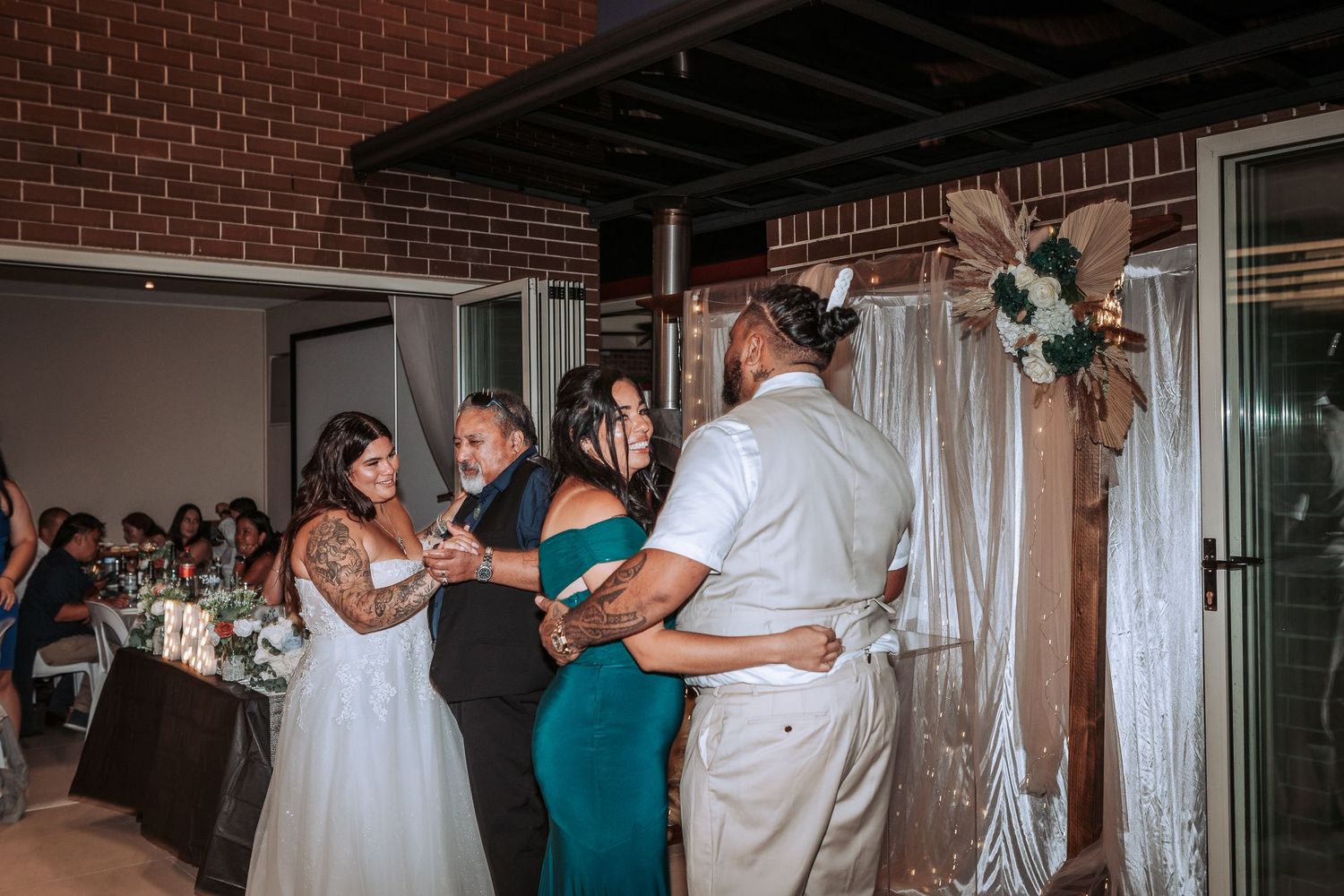 Couples dancing together at a wedding reception with white drapery and floral decorations.
